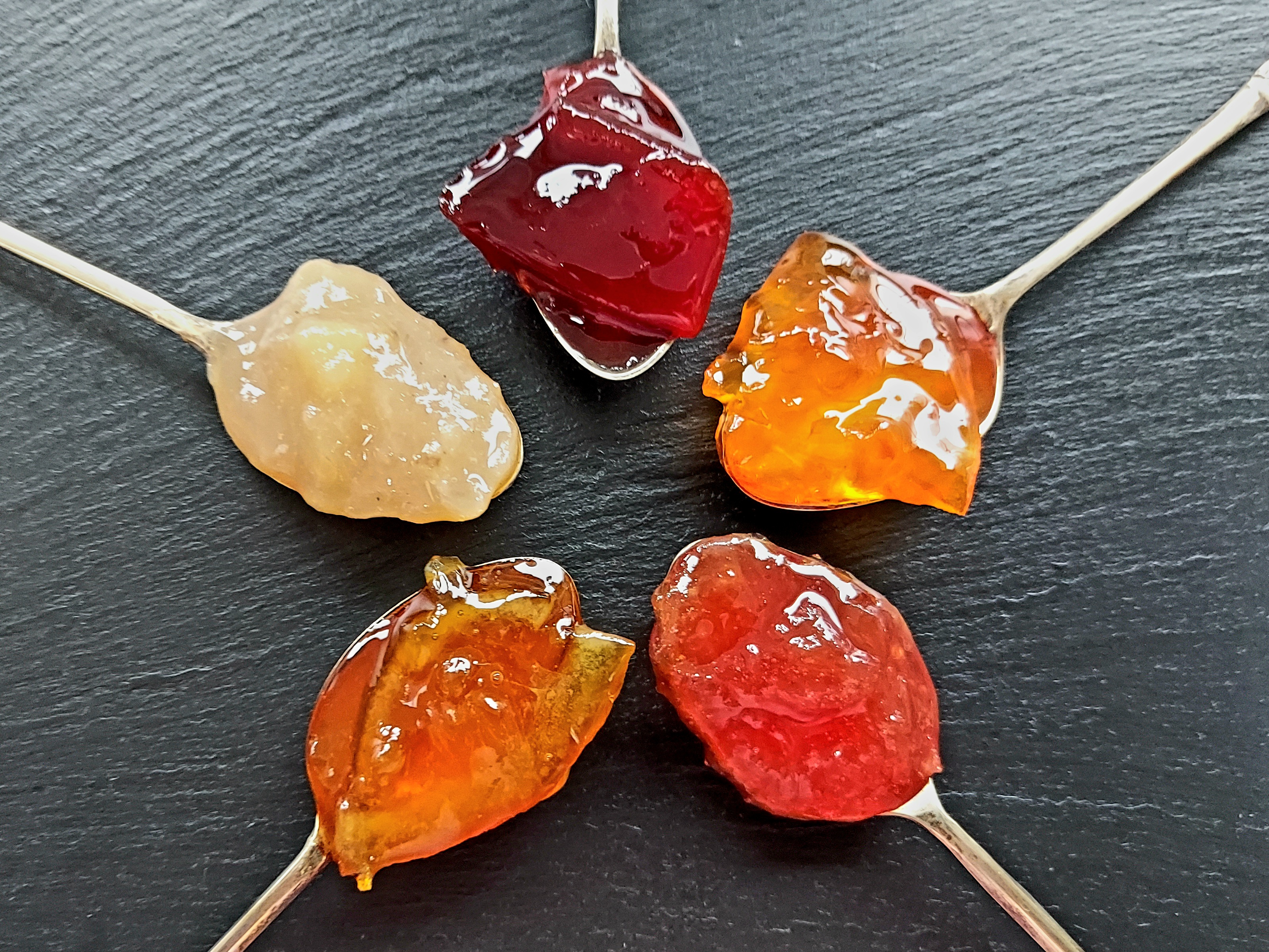 Five spoons with different jam varieties